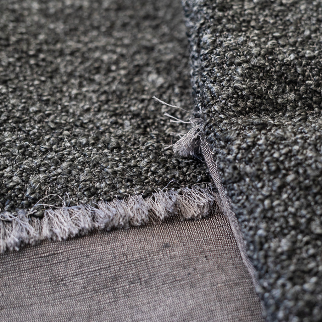 Close up of black boucle pillow with hand fringe and raw silk pillow cover