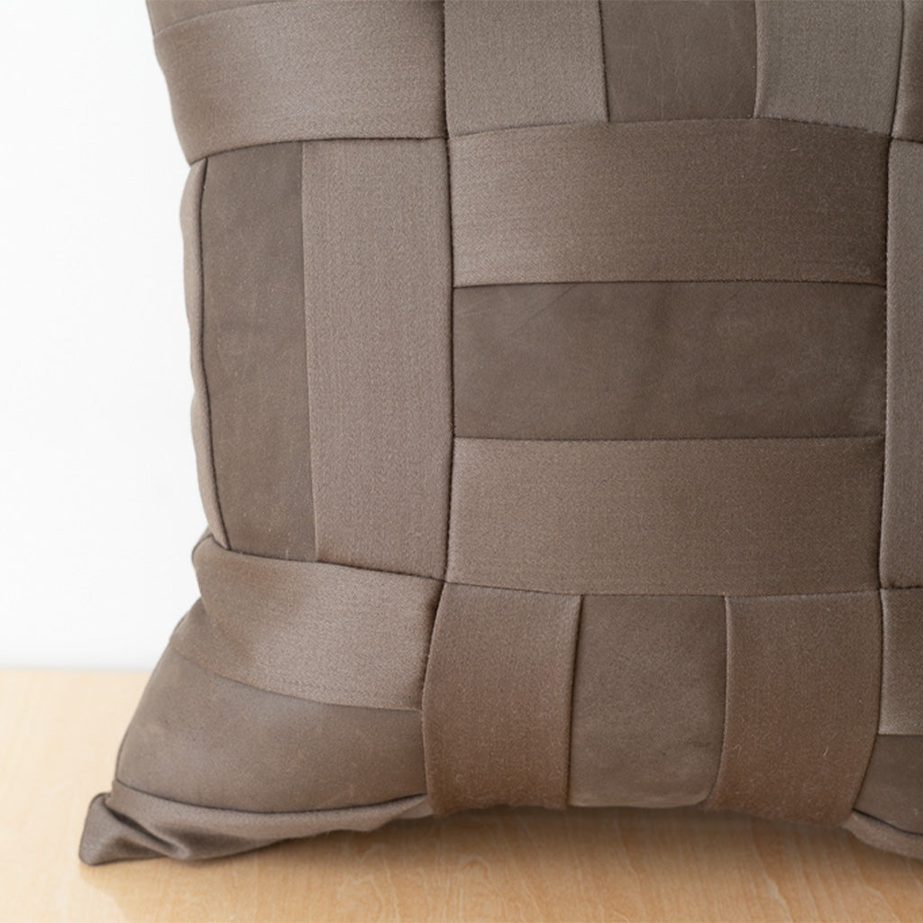 A close up detail of Chocolate Brown Leather and Wool quilted pillow on a table with white wall behind. 