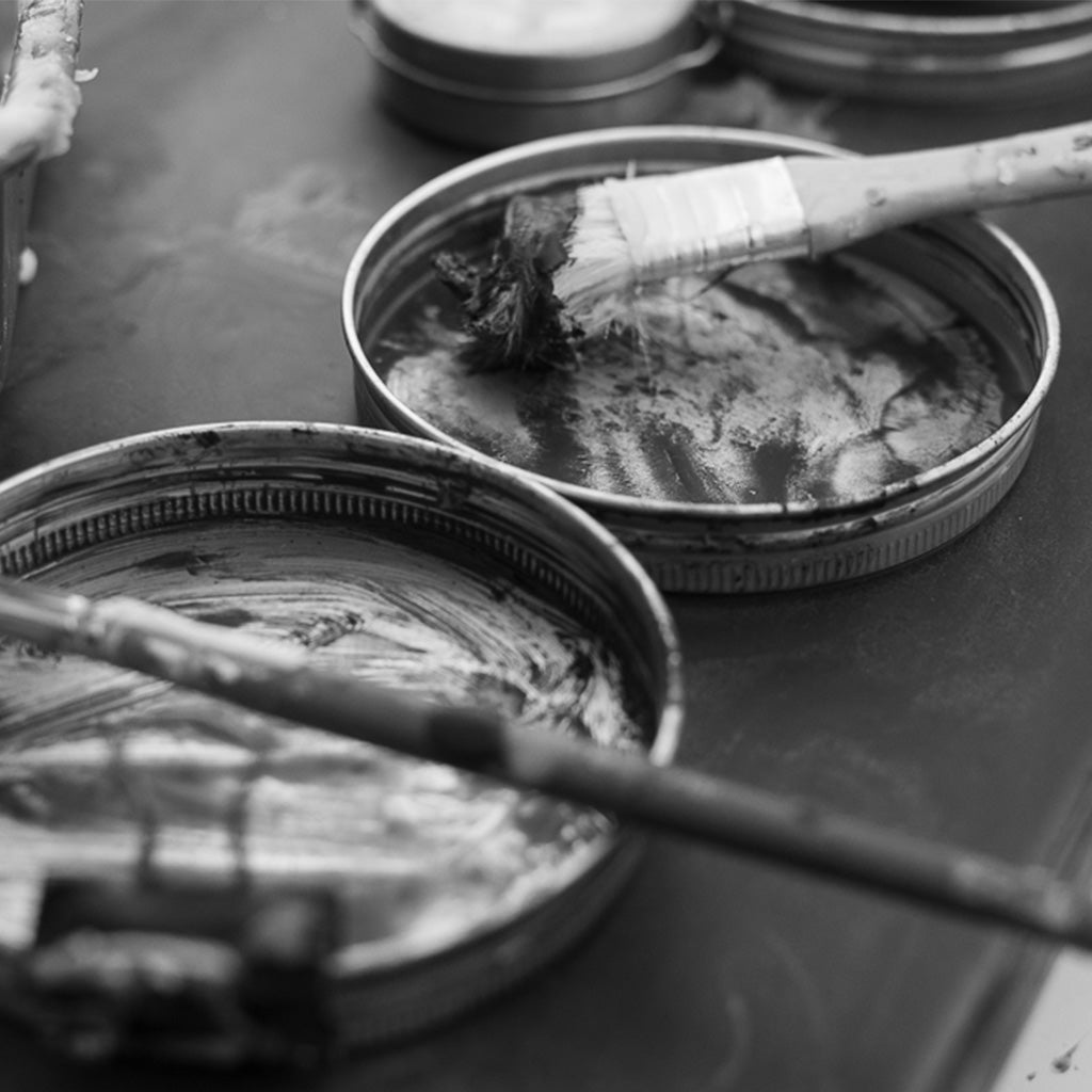 Black and white photograph of encaustic wax tins and a studio brush, ADALÉI material practice, Raleigh NC

